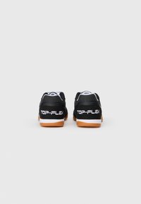 Baskets de sport noires avec une tige texturée, présentant un design perforé. Les semelles sont de couleur gomme avec le logo blanc "TOP-FLEX" sur le talon.
