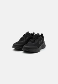 Baskets de sport noires avec une tige en mesh, un col rembourré et une semelle en caoutchouc. Design épuré avec des lacets et un logo sur le côté.