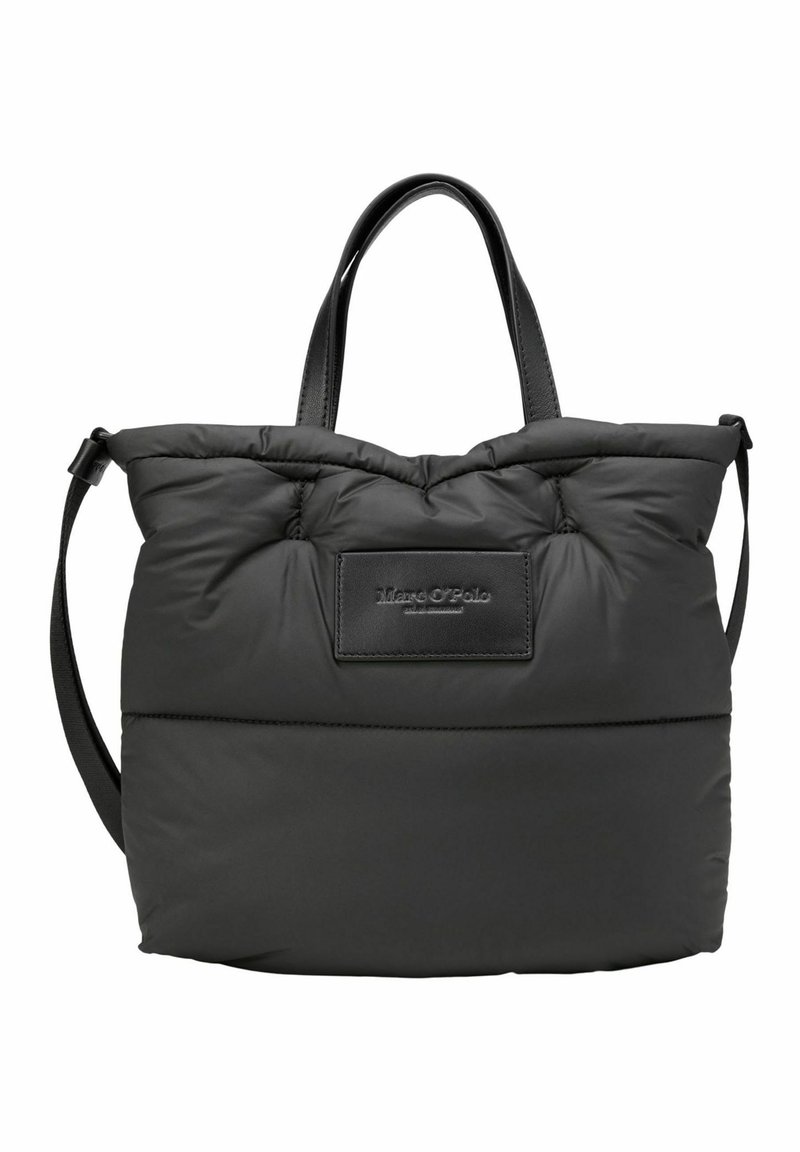 Sac cabas matelassé noir avec deux poignées et une bandoulière réglable, avec un écusson cousu à l'avant portant le nom de la marque en relief.