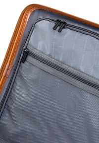 Interno di una custodia da viaggio grigia con una finitura testurizzata, presenta due tasche con cerniera e bordature arancioni delle cerniere per un contrasto.