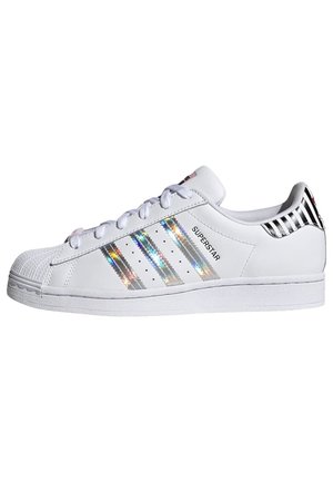 Biała tenisówka Adidas Superstar z holograficznymi paskami, wzmocnionym noskiem, białymi sznurówkami i czarnym paskowanym zapiętkiem.