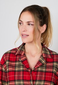 Rood en zwart geruit shirt met een zachte textuur, knoopsluiting en een kraag. Heeft een ontspannen pasvorm en contrasterende beige lijnen.