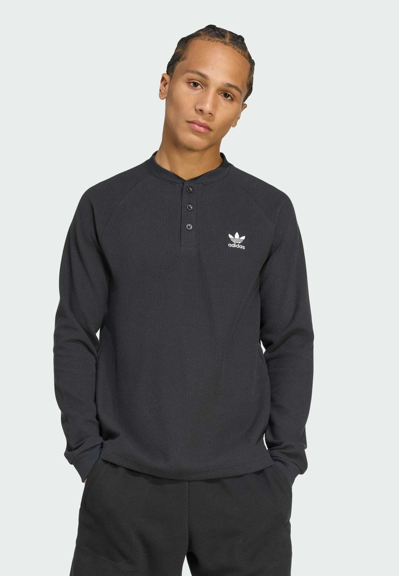 Black long-sleeve henley shirt made of textured fabric, featuring a button placket and a small white Adidas logo on the left chest.