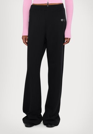 Schwarze weite Hosen aus glattem Stoff mit einem dezenten Logodetail an der Seite. Der Bund ist elastisch für zusätzlichen Komfort.