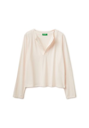 Blusa de manga larga, color beige claro, con cuello en V y corte holgado, mostrada sobre fondo blanco.