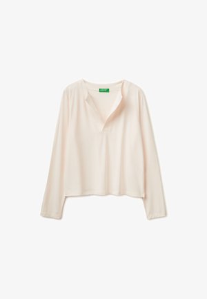 Bluzka z długim rękawem w jasnobeżowym kolorze z dekoltem w kształcie litery V i luźnym krojem, prezentowana na białym tle.