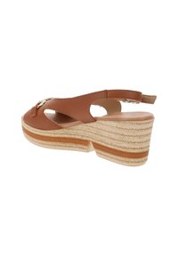 Sandalo con zeppa in pelle marrone, piattaforma in juta intrecciata, design con ritagli e cinturino sul retro; presenta un accento metallico sulla parte superiore.
