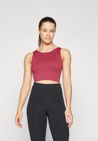 Ribbet maroon crop topp med bred utringning, sammen med høyt liv svarte leggings. Stoffet har en jevn tekstur og en kroppsnær design.