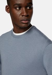 Light blue sweater with a ribbed texture, round neckline, and long sleeves. The fabric appears soft, with subtle stitching details.