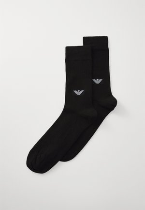 Schwarze Baumwollsocken mit gerippter Struktur, ausgestattet mit einem kleinen, weißen gestreiften Logo an der Seite. Crew-Länge Design.