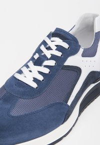 Scarpe sportive blu navy in materiale mesh e camoscio, con accenti bianchi, lacci piatti e suola in gomma spessa e testurizzata.
