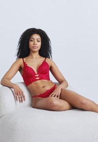 Κόκκινο δαντελένιο σουτιέν με κοψίματα, ρυθμιζόμενους ιμάντες και ταιριαστό δαντελένιο σλιπ. Το σετ διαθέτει απαλή υφή και περίπλοκα ανθισμένα σχέδια.