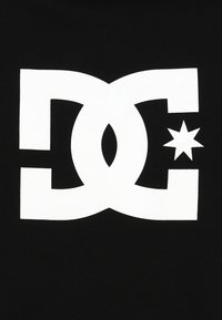 Black fabric background with a large white stylized "DC" logo, featuring a circular accent and a star on the right side.