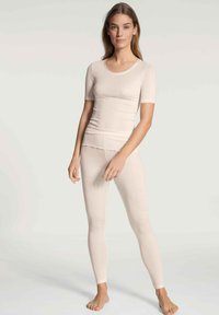 Light beige fitted t-shirt and leggings, made of a soft, stretchy fabric. T-shirt features short sleeves and a round neckline.
