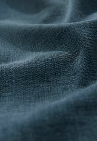 Tissu bleu foncé avec une texture douce et lisse et un léger éclat, présentant un subtil motif tissé. Accent sur les plis drapés et la réflexion de la lumière.