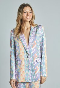 Blazer multicolor con patrones geométricos en tonos pastel, un profundo escote en V, dos bolsillos frontales y un cierre de botón único.