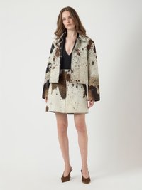 Veste courte et jupe en tissu texturé à pois dans des tons de marron et de crème, dotées de boutons-pression et d'un ourlet net.