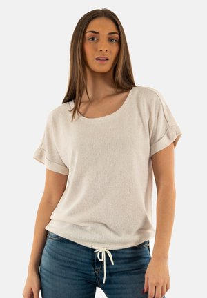 Maglione corto beige chiaro con maniche corte, scollo a barchetta, tessuto testurizzato e cordino regolabile all'orlo. Abbinato a jeans blu.