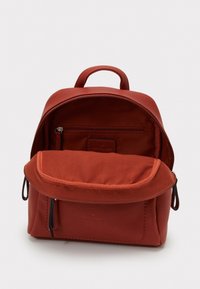 Röd läderryggsäck med en strukturerad yta, ett handtag på toppen, zippered huvudfack och en frontficka med klaff i en kontrasterande tyg.