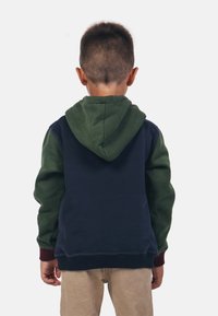 Sweat-shirt à capuche avec un corps principal bleu marine, des manches vertes et des poignets bordeaux. Tissu doux avec une coupe décontractée et une poche avant.