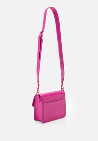 Borsa a tracolla rosa in similpelle con stampa coccodrillo. Presenta una chiusura a pattina, una cinghia regolabile e una tasca frontale per la conservazione.