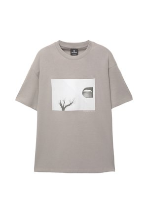 T-shirt en coton gris avec un large col rond. Présente un motif graphique rectangulaire d'un arbre et d'une forme de dôme, mettant en valeur un design minimaliste.
