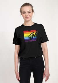 Černé tričko s krátkým rukávem s barevným logem MTV s duhovými pruhy, pod logem je nápis "MUSIC TELEVISION" v purpurové barvě.