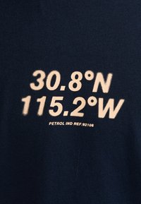 Tissu en coton bleu marine avec un grand texte crème : "30.8°N 115.2°W" et "PETROL IND REF :92168" en dessous, sur un fond uni.