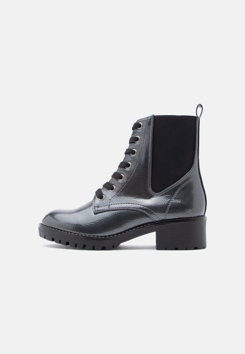 Bottine noire laquée avec talon épais, fermeture à lacets à l'avant, panneau latéral élastique et languette au talon pour un enfilage facile.