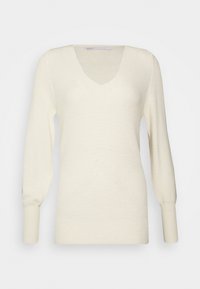 Krämfärgad stickad tröja med V-ringning, långa ärmar och textil med ribbade detaljer. Enkel och minimalistisk design.