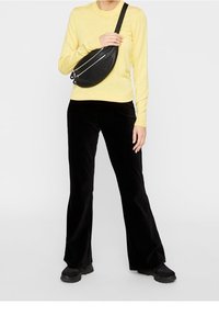 Gul långärmad skjorta, svarta kordflorsbyxor med vida ben, svart axelväska med dragkedja och svarta klumpiga skor. En enkel, avslappnad outfit.