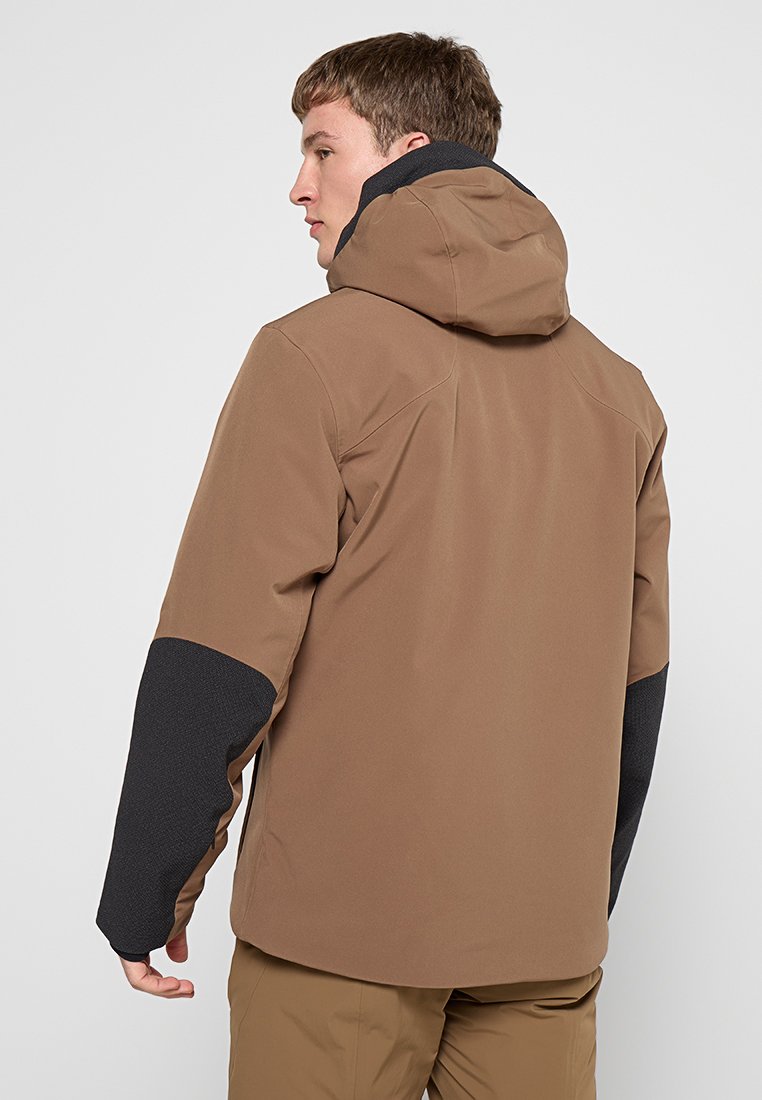 Veste imperméable marron avec capuche, manches noires texturées, design épuré et sans logos visibles. Le matériau semble lisse et durable.