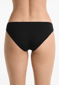 Zwarte bikini slipjes van een gladde, rekbare stof. Ontworpen met een laag uitgesneden snit en minimale bedekking, met schone randen en zonder zichtbare hardware.