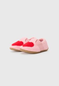 Pink slippers made from soft, textured material, featuring a red heart detail on each shoe and an elastic strap for easy wear.