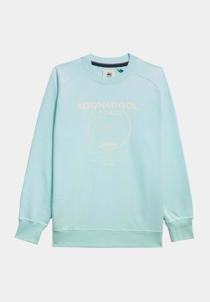 Sudadera de color azul claro con mangas largas, cuello redondo y puños de canalé. Presenta un diseño gráfico de texto en blanco en la parte frontal. Textura suave.