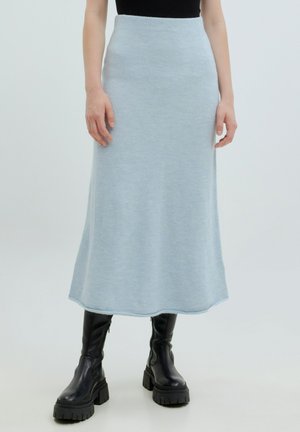 Himmelblauer Strick-Maxikleid mit glatter Textur, einer taillierten Passform und einem ausladenden Saum. Kombiniert mit schwarzen knöchelhohen Stiefeln mit dicker Sohle.