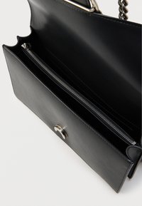 Μαύρη δερμάτινη τσάντα χειρός με κομψό σχεδιασμό, που διαθέτει θήκη με φερμουάρ και κλείσιμο με ασημί μεταλλικά στοιχεία. Ορατό ιμάντα από αλυσίδα.