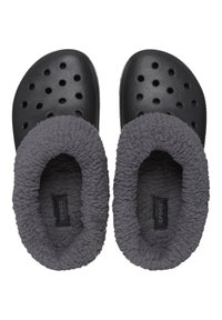 Chanclas Crocs negras con forro de forro polar gris, orificios circulares en la superficie superior y suela texturizada para agarre. Etiqueta visible en el interior.