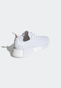 Zapatillas deportivas blancas con una parte superior de malla texturizada, contra de plástico en el talón y suela de goma. Presentan detalles en blanco y una etiqueta de logo en la lengüeta.