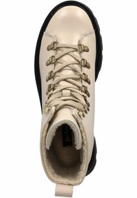 Botas de senderismo de cuero crema con suela de goma negra, ojales dorados y un diseño de cordones texturizado. Forro de forro polar visible dentro de la abertura.