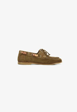 Mocassin en daim marron avec fermeture à lacets et perles en bois décoratives le long du côté, semelle en caoutchouc plate et coutures visibles.