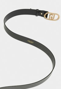 Curea din piele neagră cu o textură netedă, având o cataramă ovală aurie și un logo embosat în aur. Designul este elegant și minimalist.