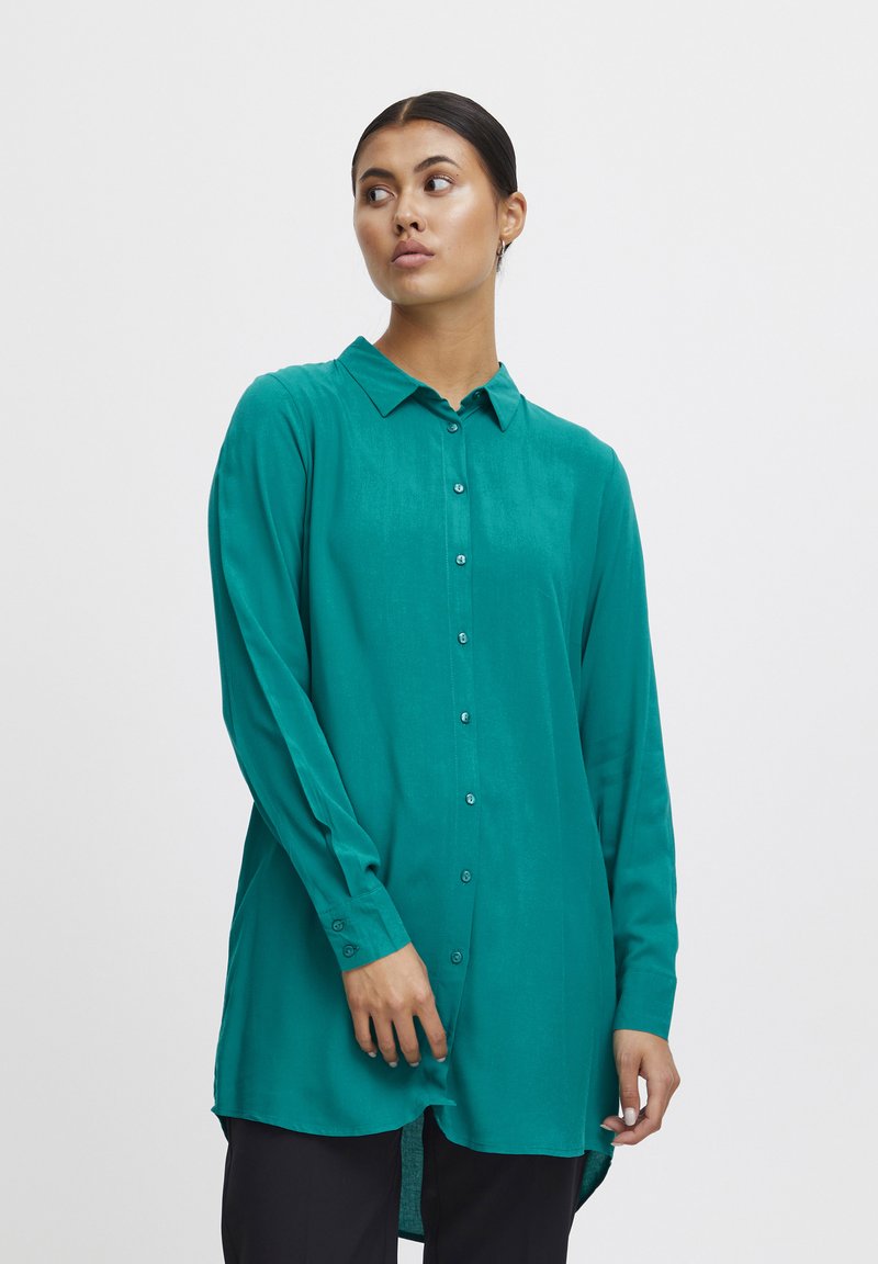 Teal long-sleeve shirt with a button front, collar, and side slits. Made from a smooth, lightweight fabric with a soft texture.