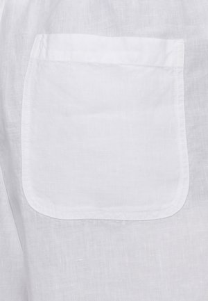 Tessuto di lino bianco con una tasca a toppa quadrata cucita, con angoli inferiori arrotondati e cuciture visibili.