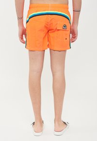 Costume da bagno arancione con accenti a righe blu e verde e una tasca posteriore. Realizzati in materiale leggero, presentano una vita con cordino.