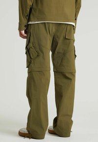 Olive cargo kalhoty s volným střihem, které mají několik bočních kapes, texturovanou látku a nastavitelné manžety. Lehce nositelný a funkční design.