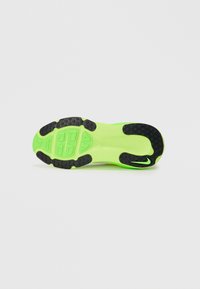 Semelle de sneaker verte vif avec des grips en caoutchouc noir texturé. Présente un design moulé, y compris des rainures et un logo près du talon.