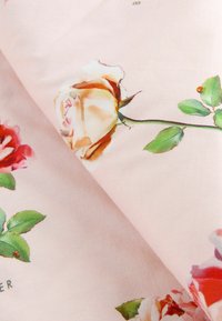 Floral fabric featuring large, painted roses in shades of pink, cream, and green on a soft pink background. Smooth texture, delicate design.