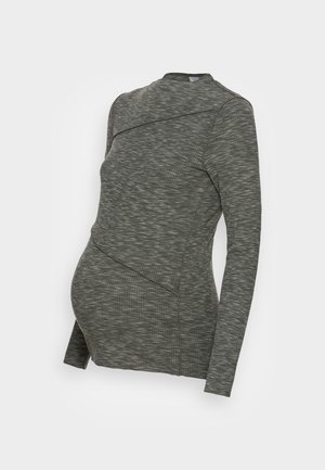 Grijze zwangerschaps top met lange mouwen van gebreide stof met textuur en diagonale naaddetails, ontworpen om plaats te bieden aan een babybuikje.