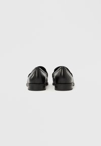 Μαύρα δερμάτινα επίσημα παπούτσια με κλασικό σχέδιο, λεία υφή, χαμηλό τακούνι και διακριτικές ραφές στο πίσω μέρος.